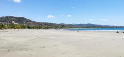 a beach with people sitting on the sand at Incroyable Villa HermoSamara in Sámara
