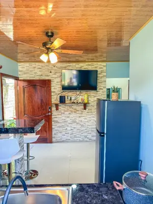 a kitchen with a refrigerator and a tv at La Fortuna Donwtown Dreams in Fortuna