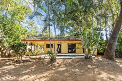 a yellow house with a swimming pool and trees at 2-Bedroom House with Pool in Playa Flamingo