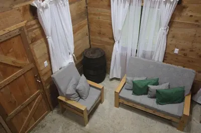 a living room with a couch and a chair and a barrel at Cabaña Trojas Valverde Vega in Trojas