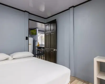 a bedroom with a white bed and a door at La Casa del Tío Carlos in San Pedro
