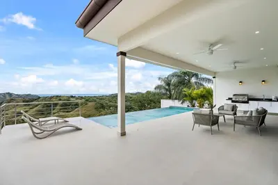 a white house with a balcony with a swimming pool at Mountaintop 4-Bedroom with Pool Huge Views in Carpintero