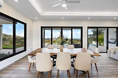a dining room with a table and chairs and large windows at Mountaintop 4-Bedroom with Pool Huge Views in Carpintero