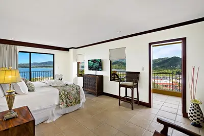 a bedroom with a bed and a view of the ocean at Remodeled Top-Floor Condo with Stunning Wrap-Around Balcony Offering Mountain, Ocean & Marina Views in Playa Flamingo