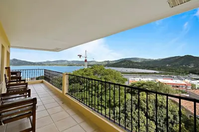 a balcony with a view of the water at Remodeled Top-Floor Condo with Stunning Wrap-Around Balcony Offering Mountain, Ocean & Marina Views in Playa Flamingo