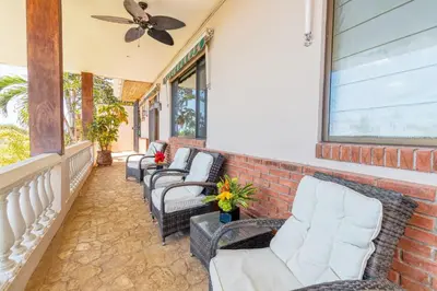 a porch with chairs and a ceiling fan at Oceanview Villa with Wrap-Around Terrace, Private Pool, Hot Tub, and Guesthouse in Playa Flamingo