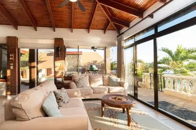 a living room with two couches and a table at Oceanview Villa with Wrap-Around Terrace, Private Pool, Hot Tub, and Guesthouse in Playa Flamingo