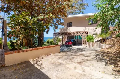 a house with a car parked in the driveway at Modern Studio Apartment with Covered Balcony, Full Kitchen, and Stunning Ocean Views in Playa Flamingo
