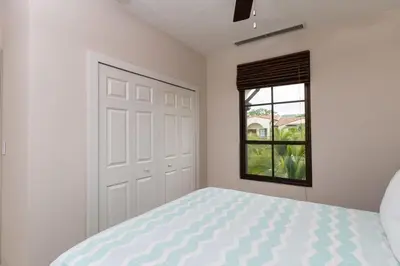 a white bedroom with a bed and a window at 3-Bedroom 2-Bath Condo Overlooking Pool in Coco