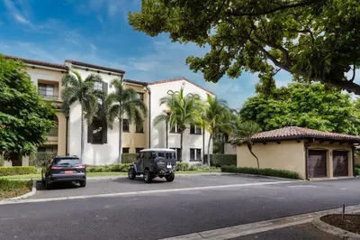 a car parked in front of a building with palm trees at 3-Bedroom 2-Bath Condo Overlooking Pool in Coco