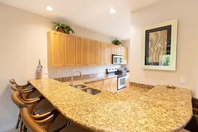 a kitchen with a granite counter top and a kitchen island at 3-Bedroom 2-Bath Condo Overlooking Pool in Coco