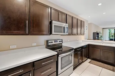 a kitchen with wooden cabinets and a microwave at Luxe 3-BD Condo on 2nd Floor Above Pool in Coco