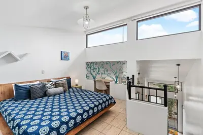 a bedroom with a bed and two windows at Bright and Spacious Loft-Style Apartment a Five-Minute Walk to the Beach in Coco