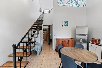 a dining room with a table and a spiral staircase at Bright and Spacious Loft-Style Apartment a Five-Minute Walk to the Beach in Coco
