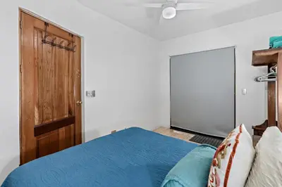 a bedroom with a blue bed and a wooden door at Bright and Spacious Loft-Style Apartment a Five-Minute Walk to the Beach in Coco