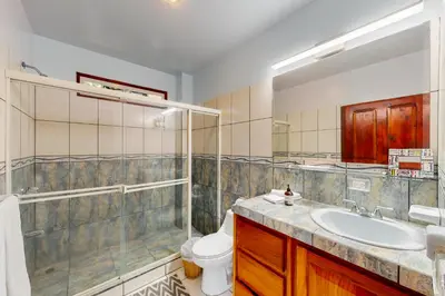 a bathroom with a sink and a shower and a toilet at Jungle Jewel in Quepos