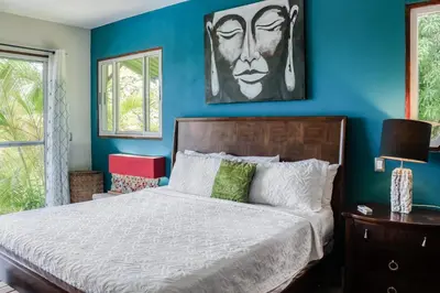 a bedroom with a bed with a blue wall at Jungle Jewel in Quepos