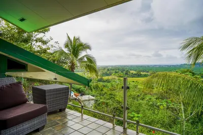 a balcony with a chair and a view of the forest at Jungle Jewel in Quepos