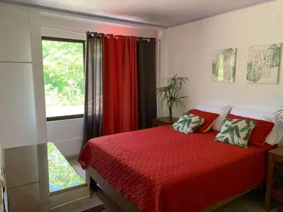 a bedroom with a red bed and a window at Calma Place in Carrillo