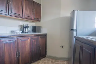 a kitchen with wooden cabinets and a refrigerator at Las Carmelas, Airport Juan Santamaría, Alajuela, San José in Alajuela City