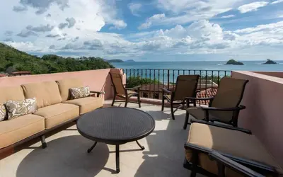 a balcony with a couch and chairs and the ocean at Calle La Ronda 15 At Las Catalinas in Playa Danta