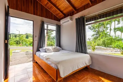 a bedroom with a bed and a large window at Chateau Arenal Hotel & Restaurante in El Castillo de La Fortuna