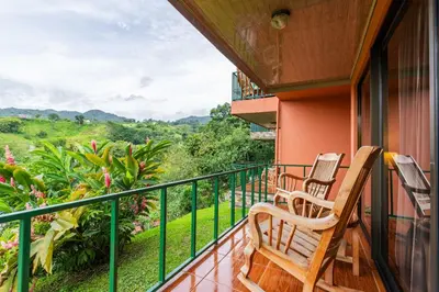 a balcony with two chairs and a view at Chateau Arenal Hotel & Restaurante in El Castillo de La Fortuna