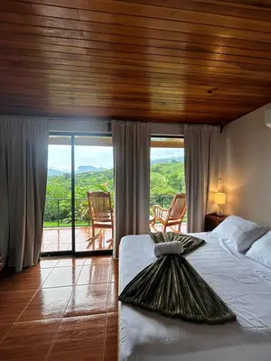 a bedroom with a bed and a balcony with sliding glass doors at Chateau Arenal Hotel & Restaurante in El Castillo de La Fortuna
