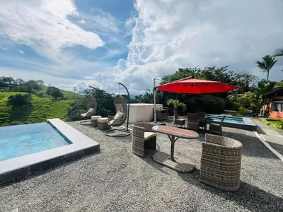a patio with a table and an umbrella and a pool at Chateau Arenal Hotel & Restaurante in El Castillo de La Fortuna