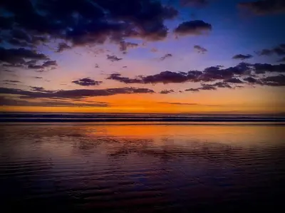 a sunset on the beach with the water at Bright & Airy new Condo, 5 min walk to Jaco Beach! in Jacó