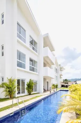 a swimming pool in front of a building at Bright & Airy new Condo, 5 min walk to Jaco Beach! in Jacó