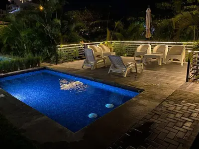 a swimming pool with chairs and a table at Bright & Airy new Condo, 5 min walk to Jaco Beach! in Jacó