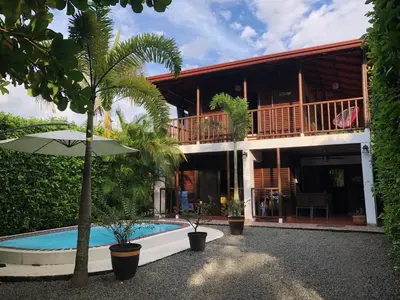 a house with a swimming pool and an umbrella at Casa Toucan mit privat Pool near NP Ballena in Uvita