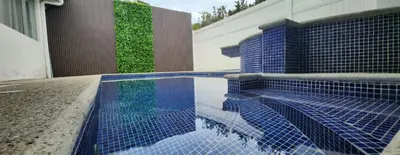 a swimming pool with blue tiles on the side of a house at Casa de playa Herradura con piscina y jacuzzi in Puntarenas