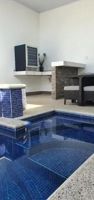 a swimming pool in a living room with a blue tiled floor at Casa de playa Herradura con piscina y jacuzzi in Puntarenas