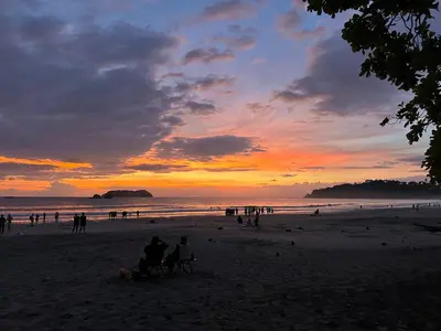 a group of people sitting on the beach at sunset at Casa Paraiso Parrita in Parrita