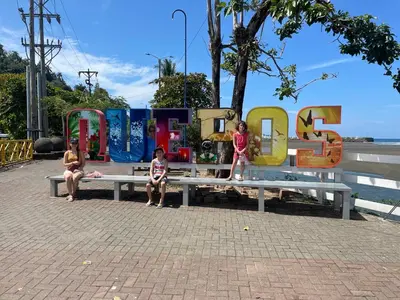 three children sitting on a bench in front of a sign at Casa Paraiso Parrita in Parrita