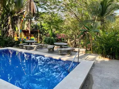 a swimming pool with picnic tables and benches next to it at Sámara Tarantela Houses, Casa Melina in Sámara