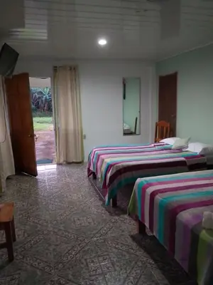 a hotel room with three beds and a door at Bijagua Blue Jeans House in Bijagua