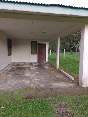 an empty building with a red door and grass at Bijagua Blue Jeans House in Bijagua