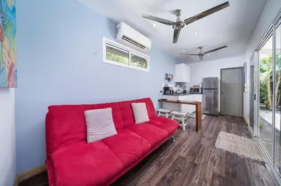 a red couch in a living room with a kitchen at Playa Potrero - Cute, modern Containerhome with pool for 2 people in Potrero