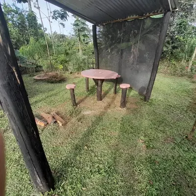 a picnic table and two stools in the grass at Chava Camping Rio Celeste in Rio Celeste