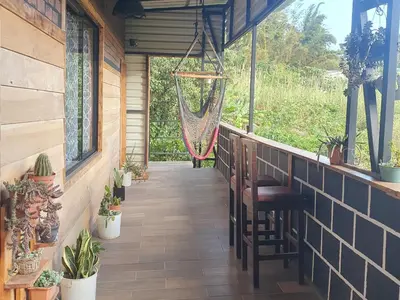 a porch with chairs and a hammock in a house at El Chaguite Monteverde in Monteverde Costa Rica