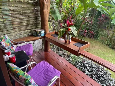 a wooden deck with chairs and a table with a vase of flowers at Toucan Villa -riverfront With Pool & Near A Beach in Uvita