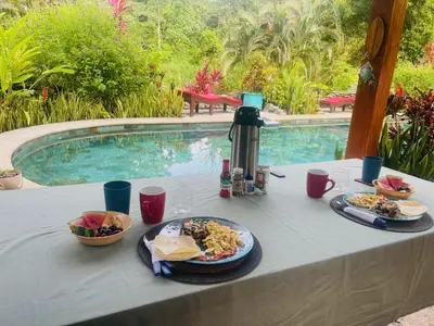 a table with food on it next to a pool at Toucan Villa -riverfront With Pool & Near A Beach in Uvita