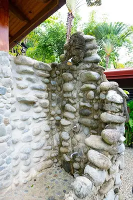 a stone wall with a statue on top of it at Toucan Villa -riverfront With Pool & Near A Beach in Uvita