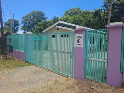 a green gate with a sign on it in front of a house at Casa Uvita Bay in Uvita