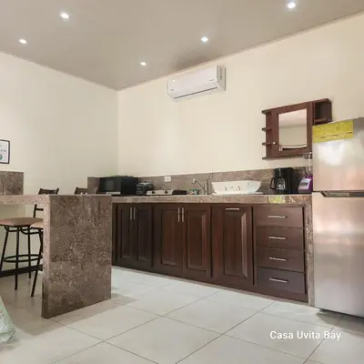 a kitchen with wooden cabinets and a stainless steel refrigerator at Casa Uvita Bay in Uvita