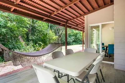 a dining room with a table and chairs and a hammock at Condo Playa Hermosa, Puntarenas in Muñeco
