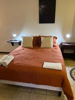 a large orange bed in a room with two tables at Frente al mar lof in Puntarenas
